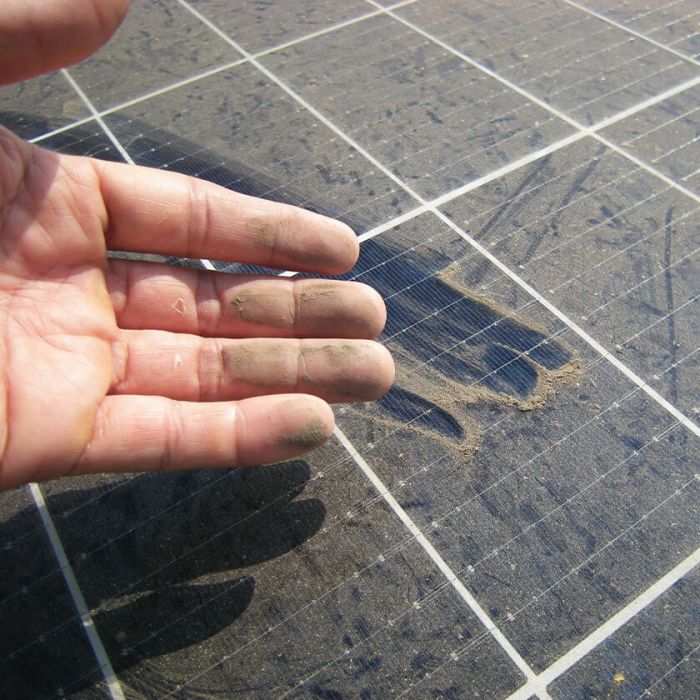 a hand showing how dirty a solar panel can get
